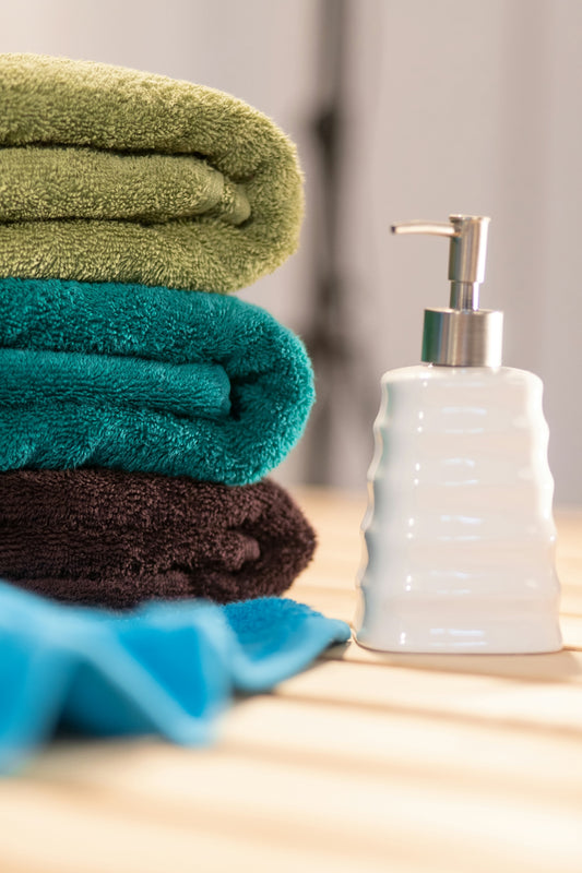 a stack of towels sitting next to a soap dispenser