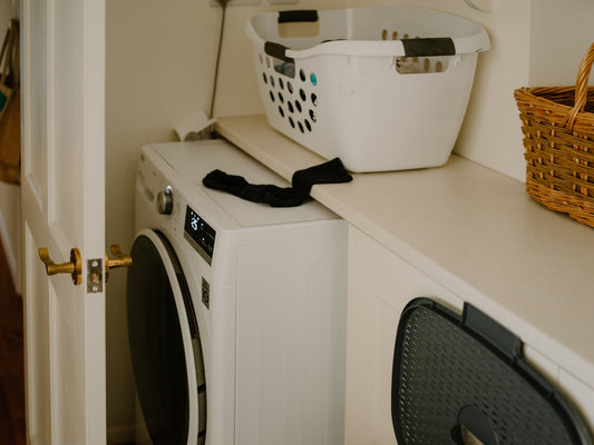 White washing machine with laundry basket and sock.
